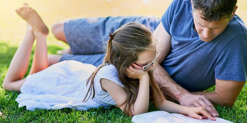 Father and daughter outside reading the bible together