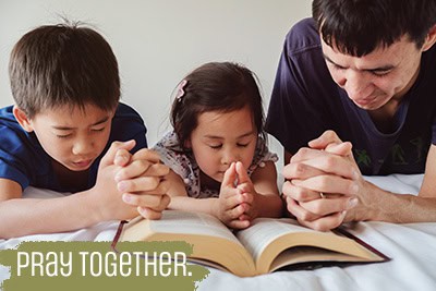 Family Praying While Lying On Bed At Home