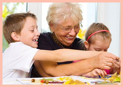 Grandmother,with,grandchildren,applying,a,dry,maple,leaves,using,glue